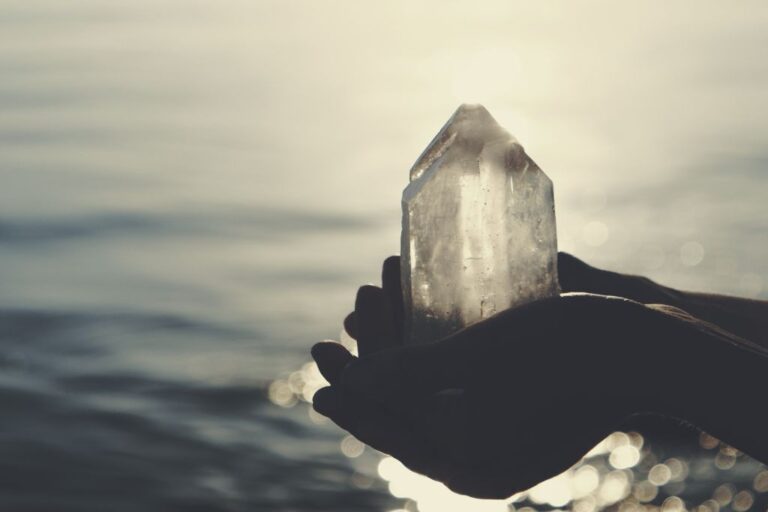 hands holding out crystal by the beach