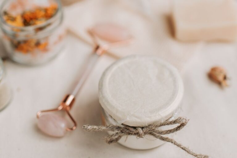 crystal roller and face cream with dried flowers on cream background