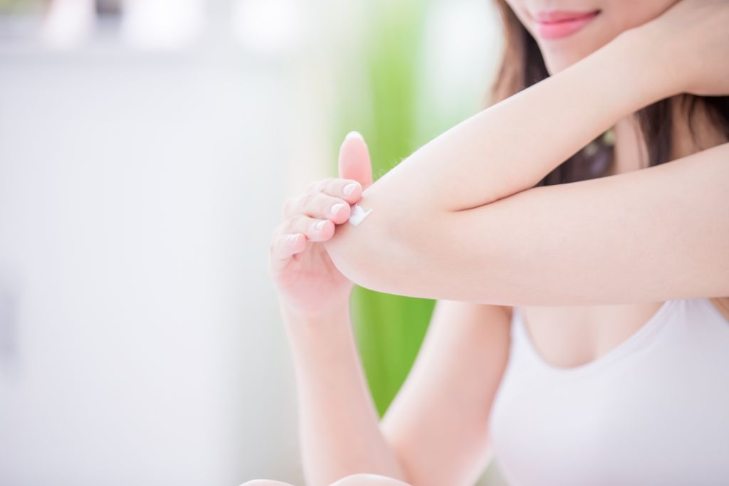 woman applying cream on her elbows
