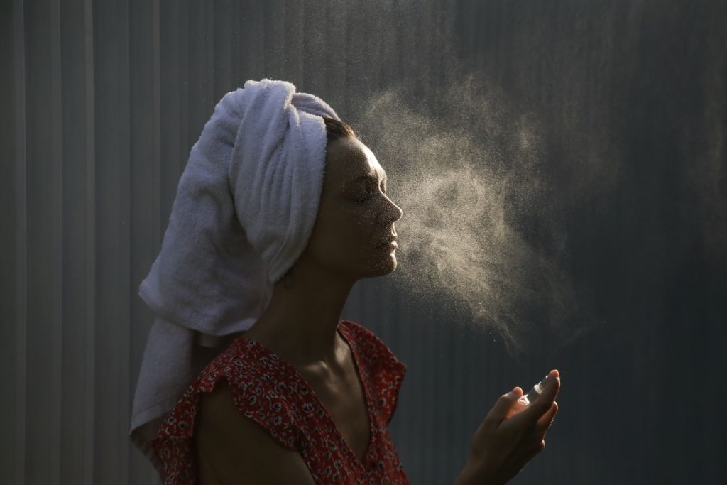 woman spraying mist on her face
