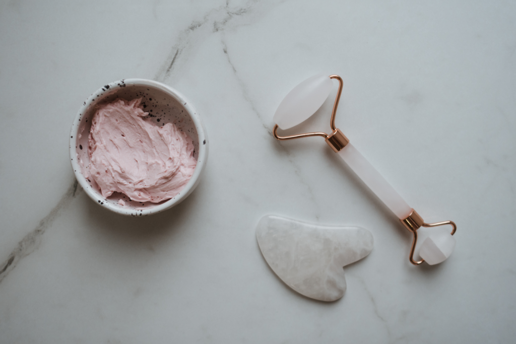 Gua sha tools and face cream on a marble background