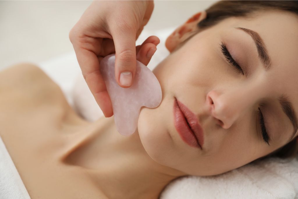 woman having a facial massage with gua sha