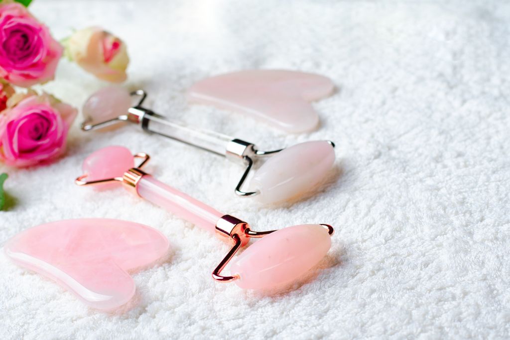 Rose quartz gua sha and face rollers on white