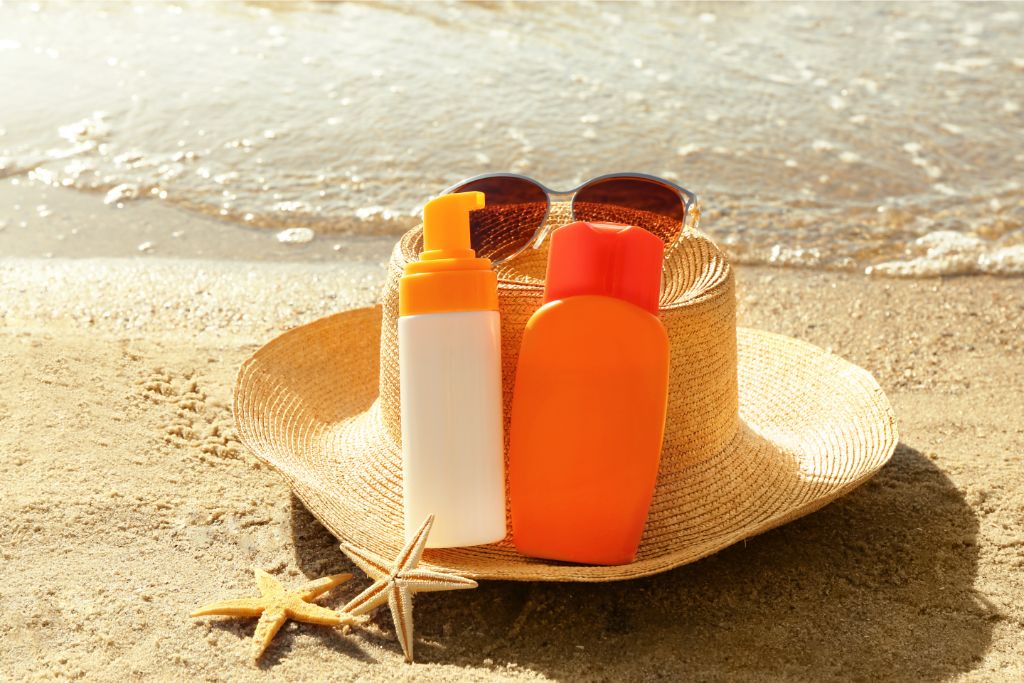 sun block lotion, hat and sunglasses on the beach